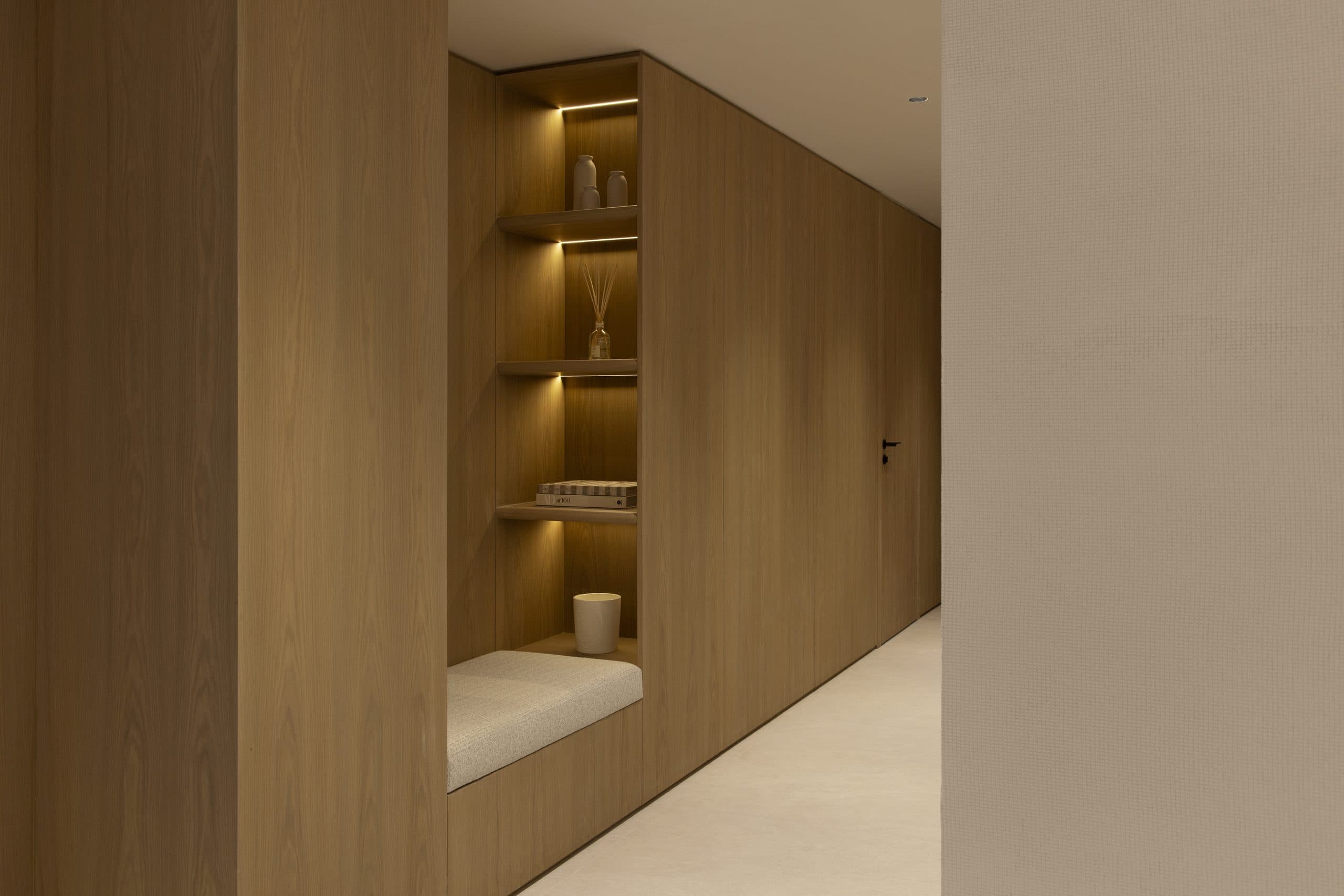 Oak-panelled hallway with a lit display niche and an upholstered bench seat